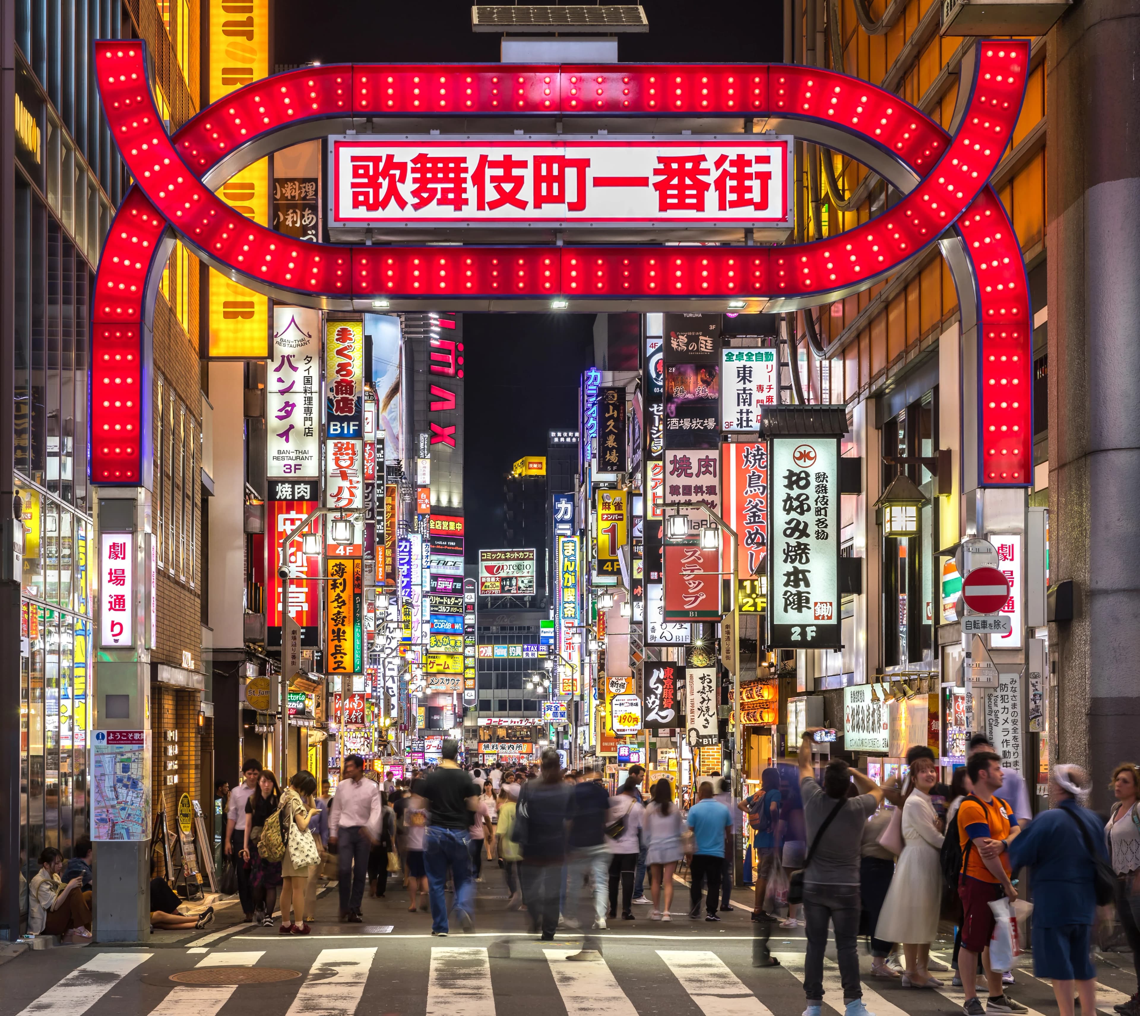Kabukicho in Shinjuku at night, with a red gate and layers of colourful illuminated signs.